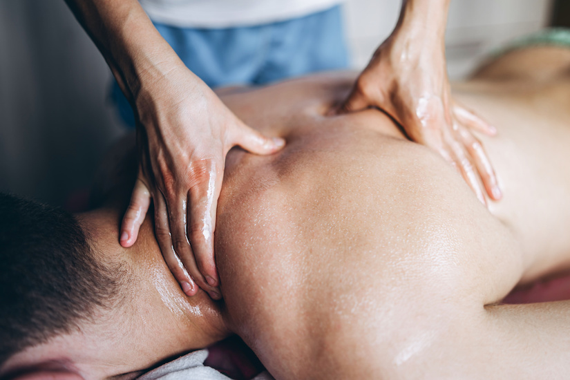 A woman physiotherapist doing back massage for a man in the medical office. Closeup of hands doing massage